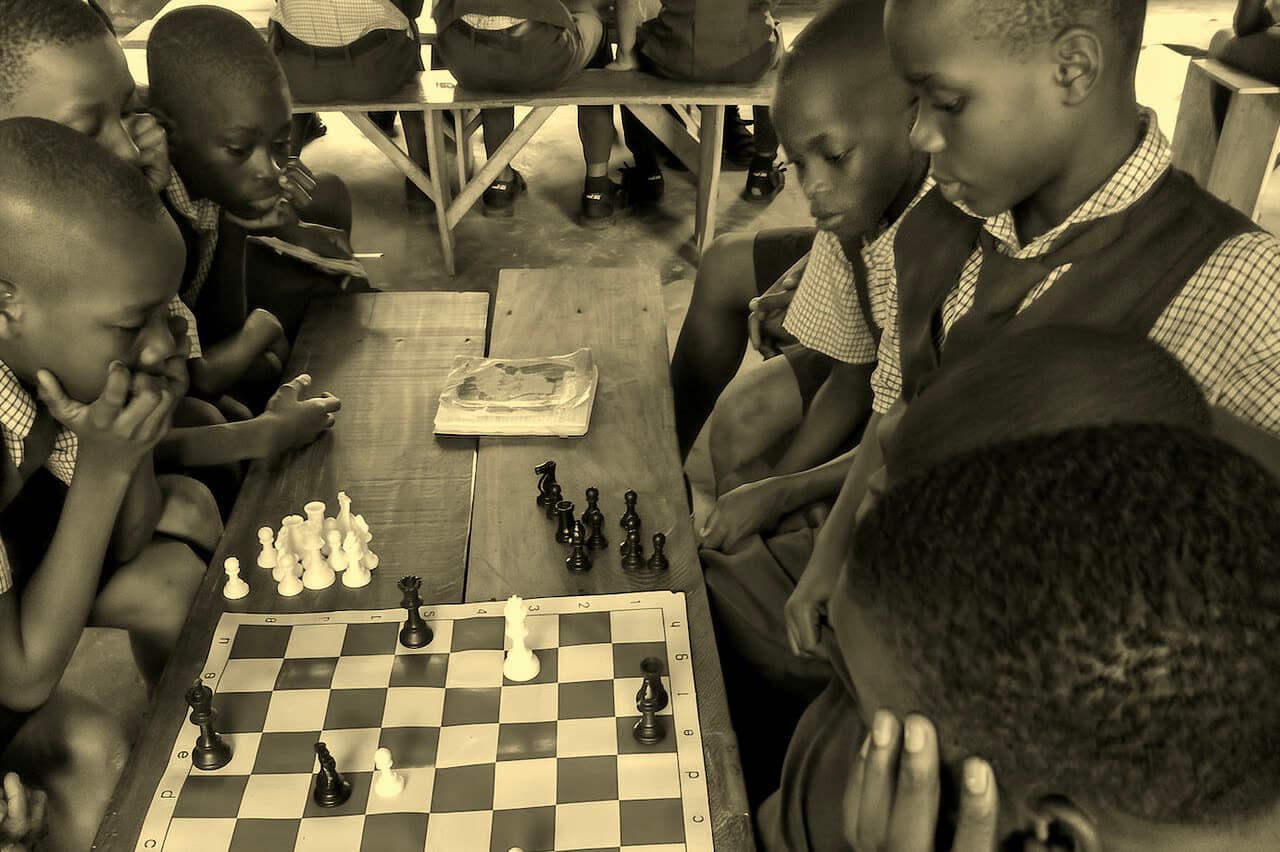 Schoolchildren in uniform gathered around a chessboard during a lesson